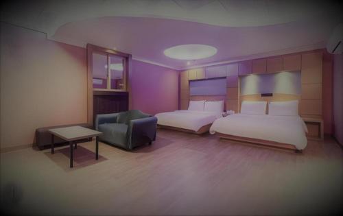 a hotel room with two beds and a chair at Hotel Head-One in Uijeongbu