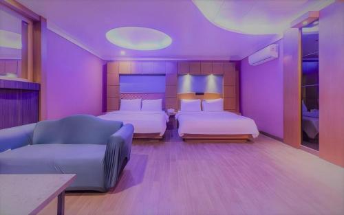 a purple room with two beds and a couch at Hotel Head-One in Uijeongbu