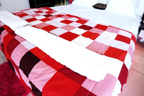 a bed with a red and white checkered blanket at Palm Suite With Sky Terrace Penthouse 11th Floor in Rajkot