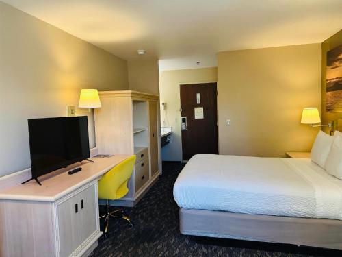a hotel room with a bed and a desk with a television at Days Inn by Wyndham Seatac Airport in SeaTac