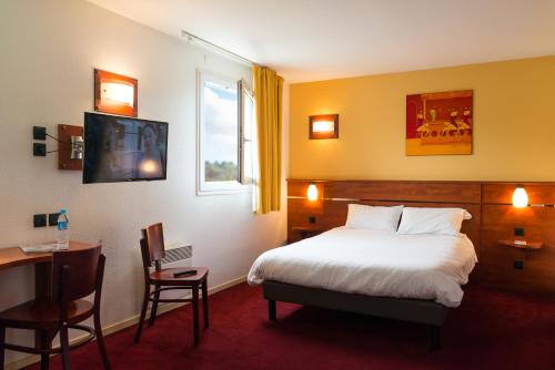 セソン・セヴィニェにあるBrit Hotel Rennes Cessonのベッド、デスク、テレビが備わるホテルルームです。