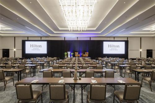a large room with tables and chairs and two screens at Hilton Arlington Rosslyn The Key in Arlington