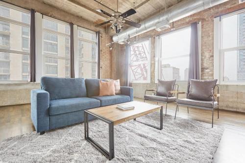 a living room with a blue couch and two chairs at Reside Houston Downtown, a Wyndham Residence in Houston