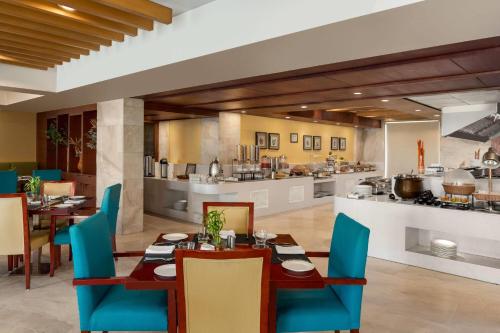 a dining room with tables and chairs and a kitchen at Ramada by Wyndham Ghaziabad Vasundhara in Ghaziabad