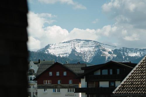 a snow covered mountain in the distance behind buildings at Das.Hochgrat in Oberstaufen