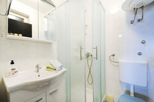a white bathroom with a shower and a sink at Apartment Doris in Šibenik