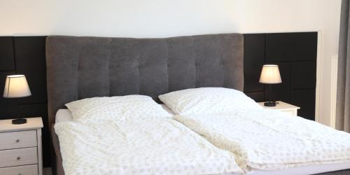 a bed with two white blankets and two night stands at Ferienglück Rosenheim in Rosenheim