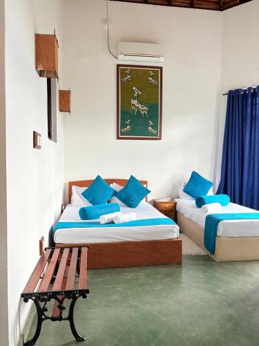 a bedroom with two beds with blue pillows and a bench at Bethel Rest Homestay in Kandy