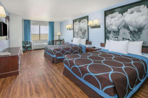 a hotel room with two beds and a television at Super 8 By Wyndham Garland North Dallas Area in White Rock