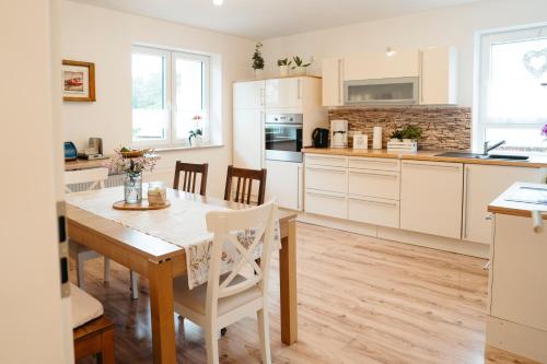 a kitchen with white cabinets and a table and chairs at Ferienwohnung Ohne Gleichen 