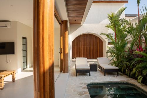 an indoor patio with a pool and a table and chairs at Modern 1BR with Rooftop Rice Fields & Seseh Beach Panorama in Cemagi