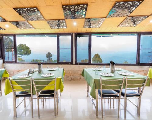 a dining room with green tables and chairs and windows at Flutter Hotels & Resort in Lansdowne