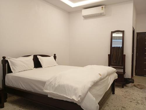 a bedroom with a bed with white sheets and a mirror at Hotel Har Niwas in Udaipur