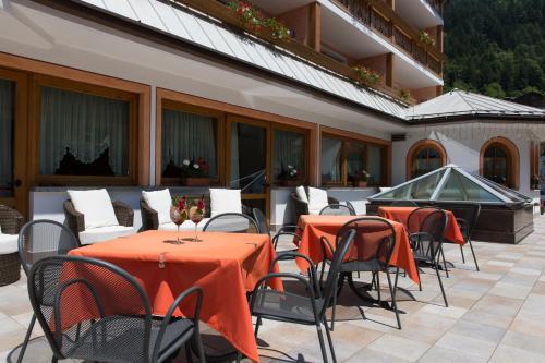 a patio with tables and chairs and a hot tub at Hotel Cristina in Pinzolo