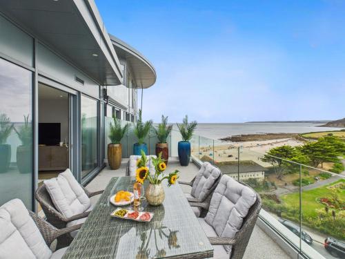 a table and chairs on a balcony with a view of the beach at Skydeck at The Liner – Stylish 2-Bed / 2-Bath Top Floor with Panoramic Sea Views in Falmouth