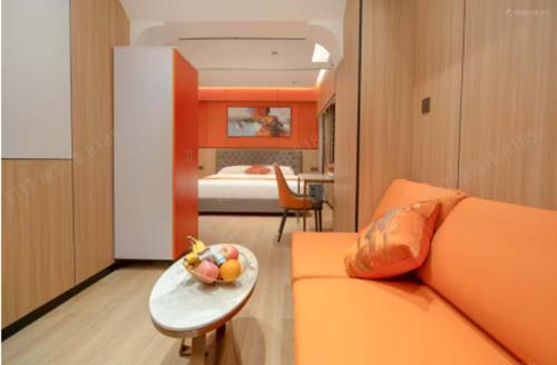 a living room with an orange couch and a plate of fruit at Chengxing Hotel Apartment (Wanyue City Plaza Branch) in Lung Wa