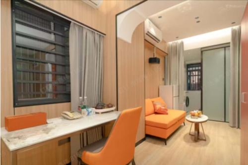 a living room with an orange chair and a window at Chengxing Hotel Apartment (Wanyue City Plaza Branch) in Lung Wa