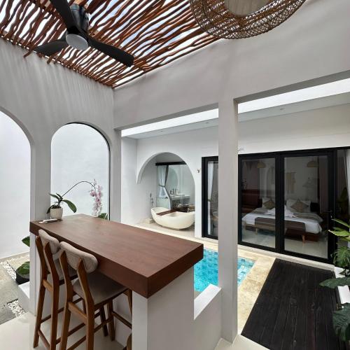 an open kitchen and dining room with a table and a bedroom at Maithala Villa Kuta Bali Near Airport in Kuta