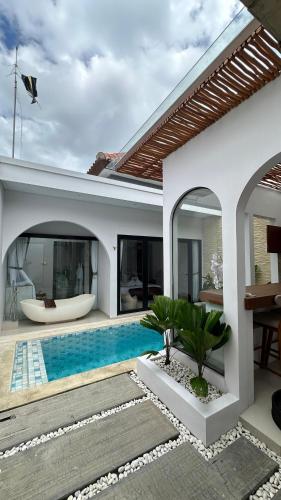 a villa with a swimming pool and a house at Maithala Villa Kuta Bali Near Airport in Kuta