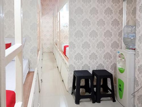 a small bathroom with two stools and a refrigerator at RedDoorz Hostel at Luna Bunkbed Malioboro in Jarakan