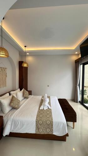 a bedroom with a large white bed and a window at Maithala Villa Kuta Bali Near Airport in Kuta