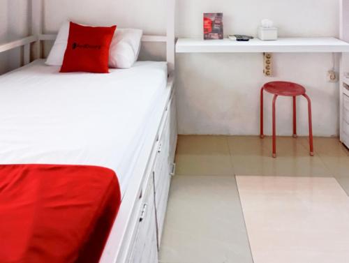 a bedroom with a bed with a red pillow and a stool at RedDoorz Hostel at Luna Bunkbed Malioboro in Jarakan