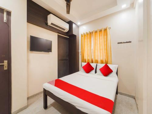 a bedroom with a bed with red pillows and a tv at Collection O MA Chidambaram Stadium Sarvanas Park in Chennai