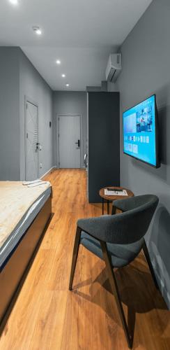 a bedroom with a bed and a chair and a flat screen tv at Capital City Hotel in Baku
