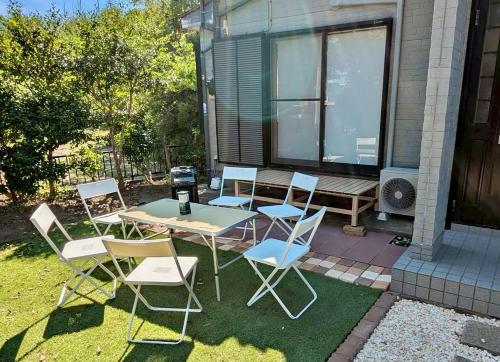 a patio with a table and chairs and a bench at Spacious Family Home Near Beach Park & Playground in Hasunuma