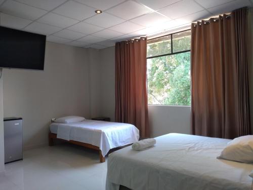 a bedroom with two beds and a large window at Hospedaje bolognesi in Piura