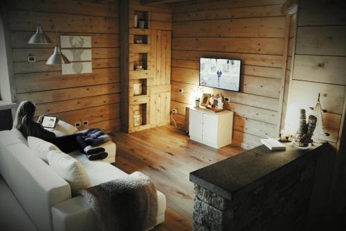 a woman sitting on a couch in a living room at Appartamento Le Chalet in Albosaggia