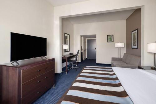 a hotel room with a bed and a flat screen tv at Wingate by Wyndham Augusta Fort Eisenhower in Augusta