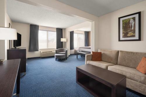 a living room with a couch and a table in a hotel room at Wingate by Wyndham Augusta Fort Eisenhower in Augusta
