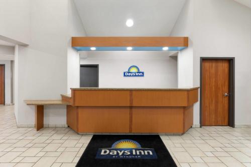 a desk in a room with a day inn sign on the wall at Days Inn by Wyndham Tulsa Central in Tulsa