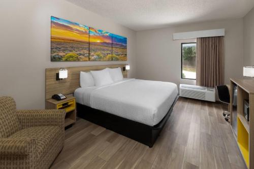 a hotel room with a bed and a chair at Days Inn by Wyndham Tulsa Central in Tulsa