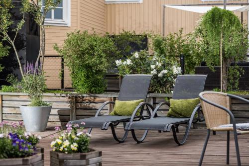 two chairs and a table on a deck with flowers at Home Hotel Cardinal in Växjö