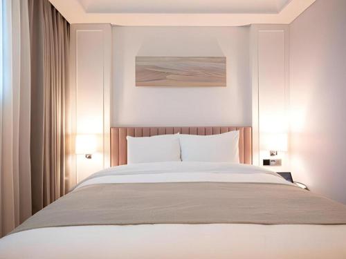 a bedroom with a large white bed with two lamps at HOTEL D EDITION in Daejeon