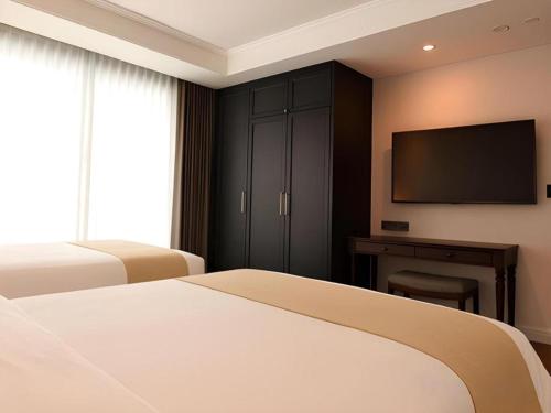 a bedroom with two beds and a flat screen tv at HOTEL D EDITION in Daejeon