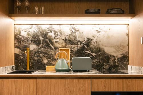 a kitchen counter with a sink and a marble wall at Los 36 by GRUPO CCOMMO in Murcia