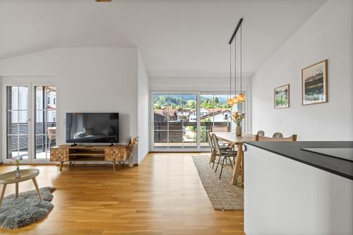 a living room with a television and a table with chairs at Sunset Club - Nesselwang Chalets Nr 1 in Nesselwang
