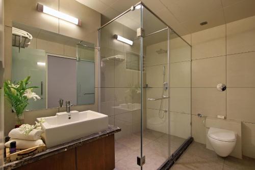 un bagno con lavandino e doccia in vetro di Prakruti Resort a Vadodara