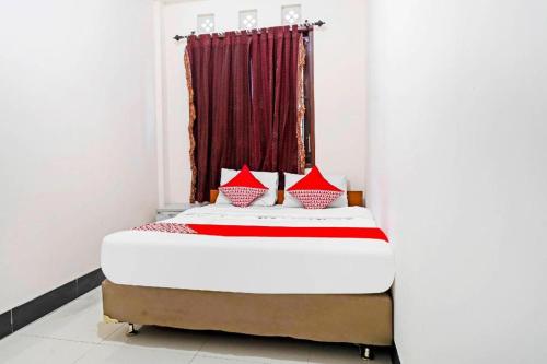 a bedroom with a bed with red pillows at Hotel O Jawara Guest House Syariah in Bandung