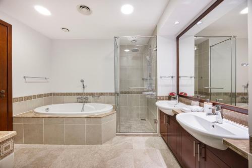 a bathroom with two sinks and a tub and a shower at Fairmont North 2BR 2 Balconies Sea View in Dubai