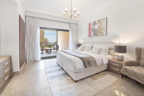 a white bedroom with a bed and a chair at Fairmont North 2BR 2 Balconies Sea View in Dubai