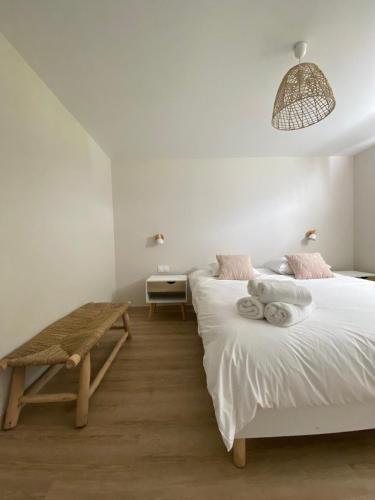 a white bedroom with two beds and a bench at Cottage Stelie in Tocqueville-en-Caux