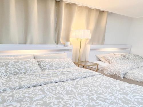 a white bedroom with two beds and a lamp at HeiStay-30sec from Hongdae SubwayStop-Elevator in Seoul