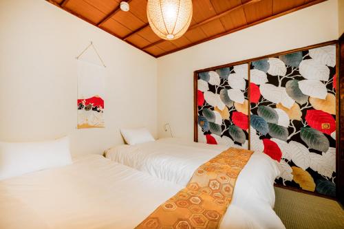 two beds in a room with a mural on the wall at KAME Inn Osaka in Osaka