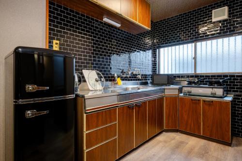 a kitchen with a black refrigerator and a sink at KAME Inn Osaka in Osaka