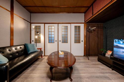 a living room with a leather couch and a table at KAME Inn Osaka in Osaka