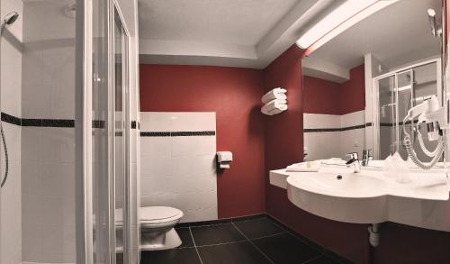 a bathroom with red walls and a toilet and a sink at Ace Hotel Montluçon in Saint-Victor